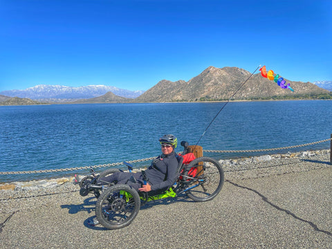 a woman on a trike in front of a lake with a mountain in the distance