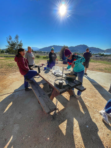 a group of campers around a table preparing food