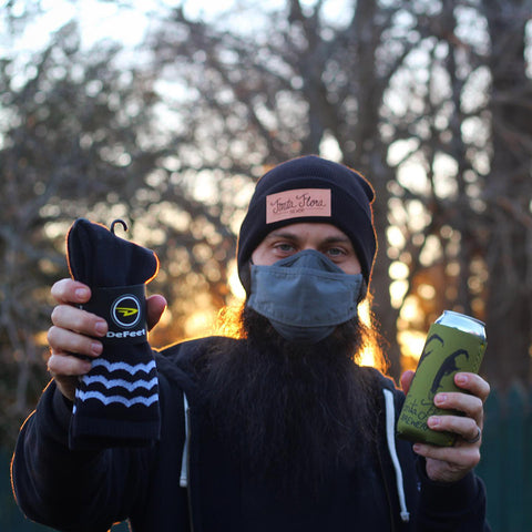 man holding a beer and custom socks from the Fonta Flora Brewery