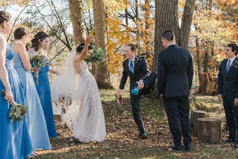 A groom shows his sock to his surprised bride and their wedding party