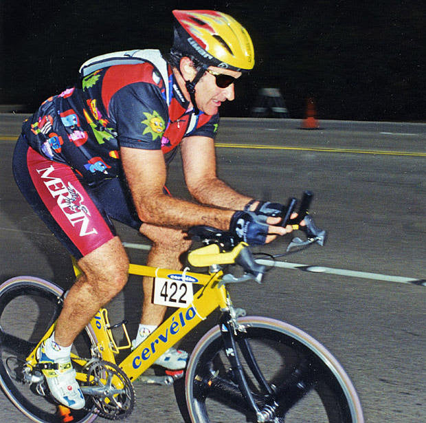 Robin Williams in full cycling gear riding on a bike