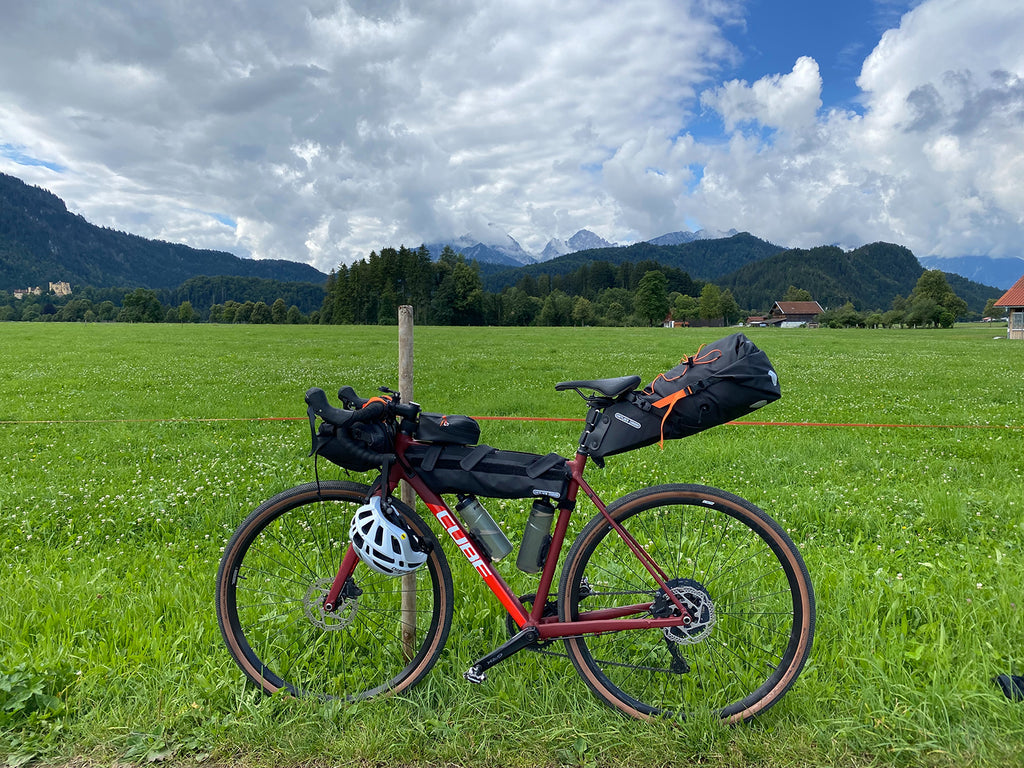 a bike with packs stands in front of a field with mountains in the distance