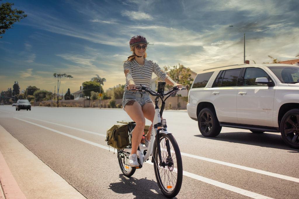 a woman riding an e-bike in the bike lane along a road