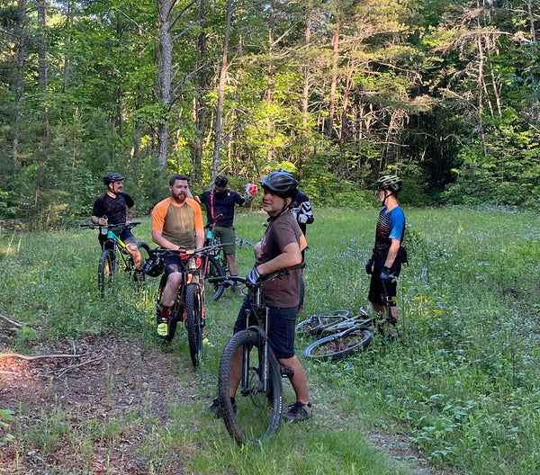 a group of sweaty mountain bikers in the woods