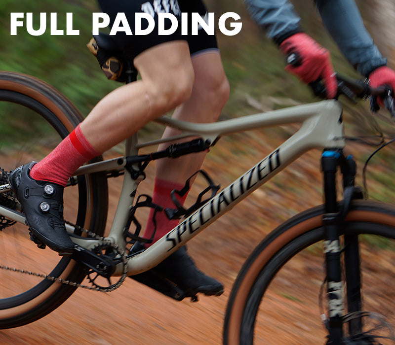 a man riding a bike on a trail wearing red wool blend cycling socks