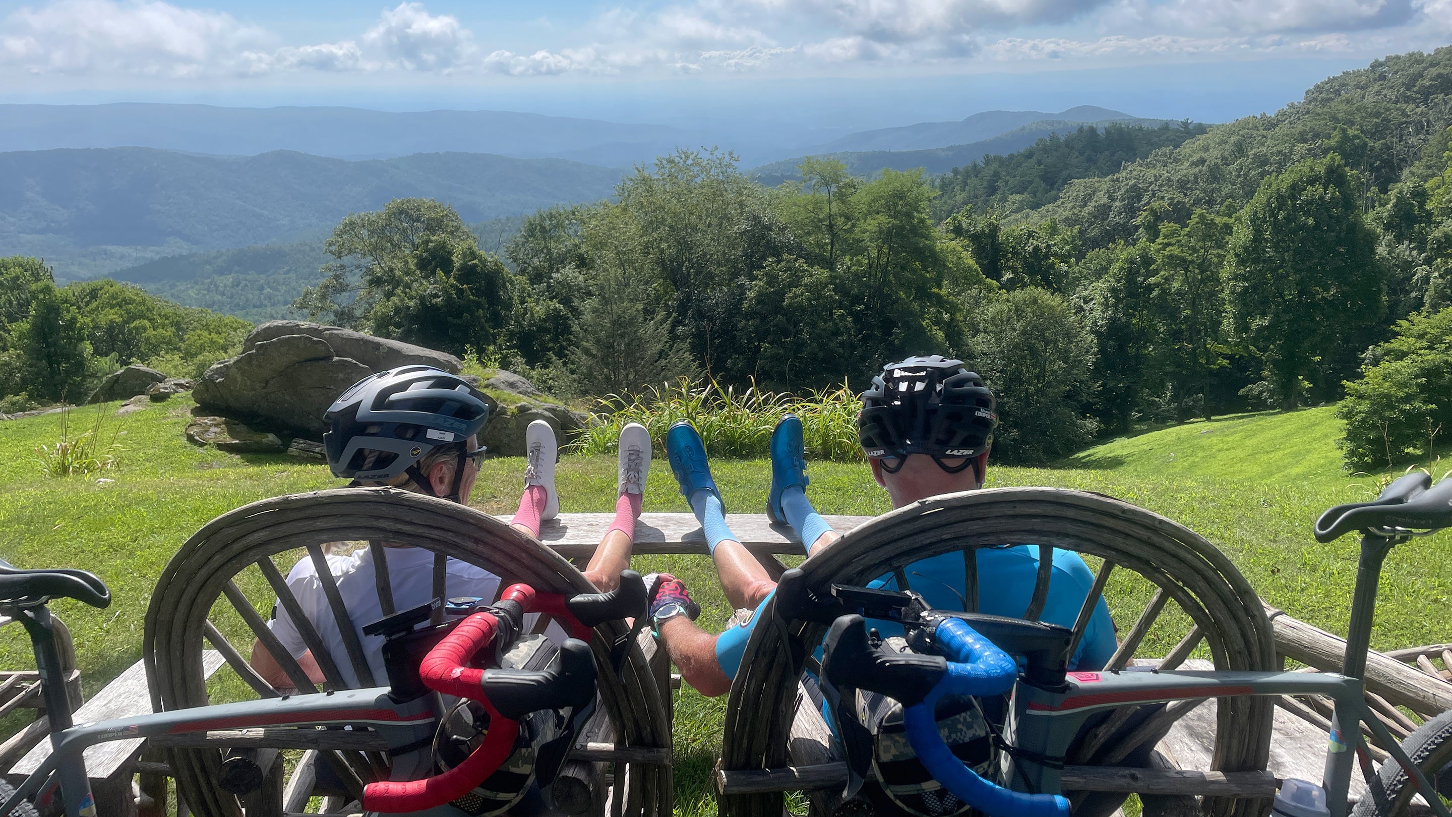 Shane and Hope Cooper sit holding hands, taking a cycling break on the top of a mountain