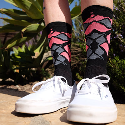 Custom DeFeet cycling socks in black with a pink and grey pattern on feet wearing white shoes