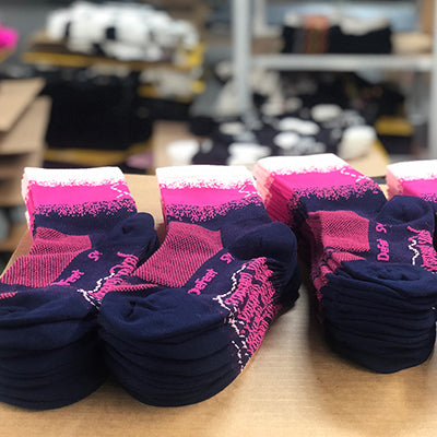 Custom DeFeet cycling socks in blue and pink in stacks on a table