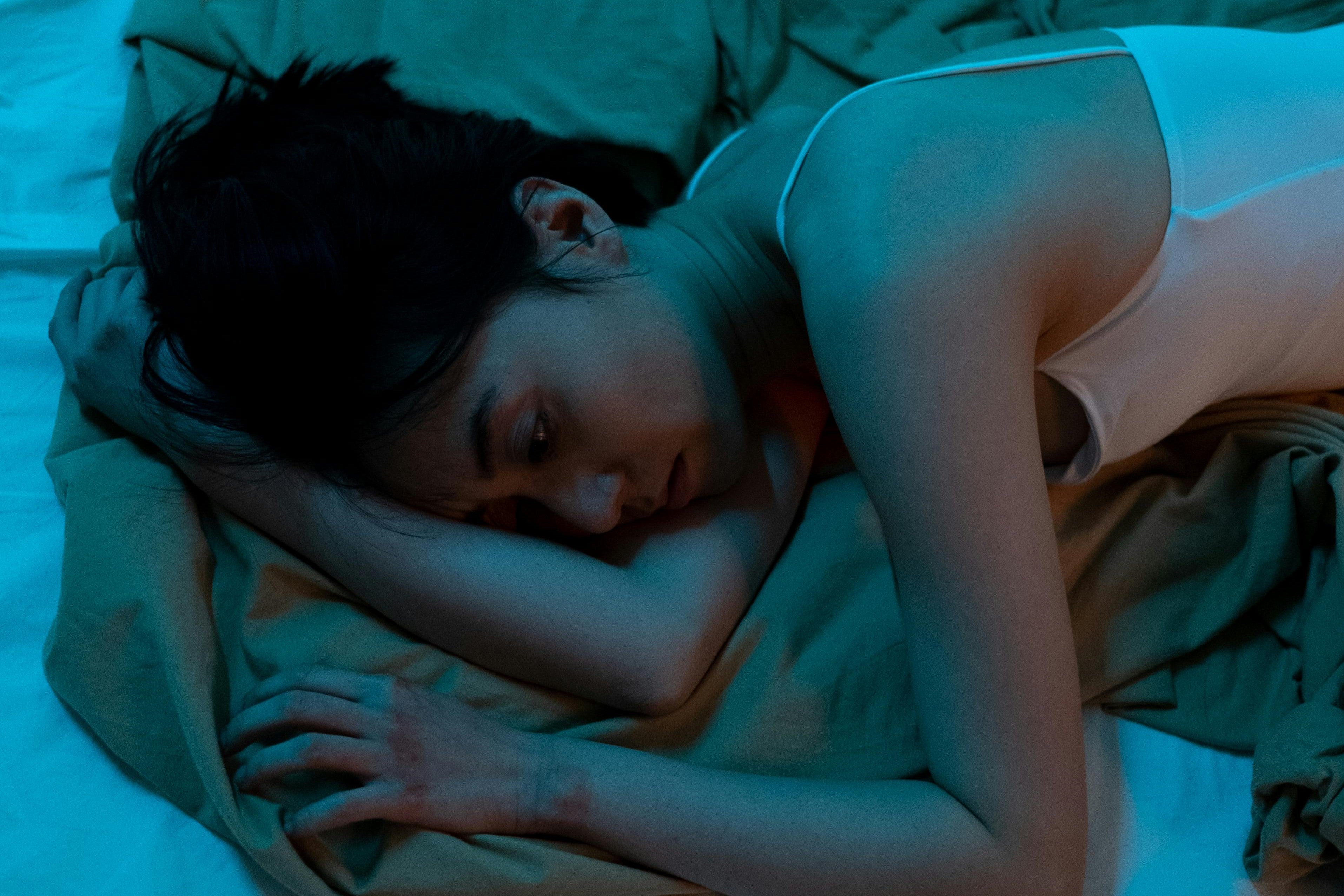 A Stressed Woman in White Tank Top Lying on Bed