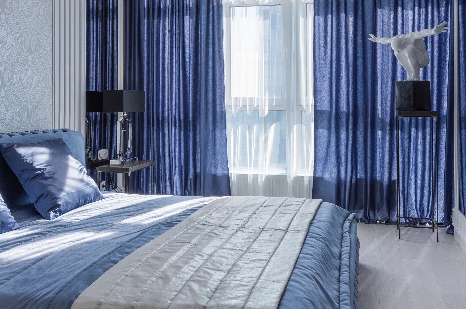 Interior of bedroom with pearl wallpapers and blue curtains