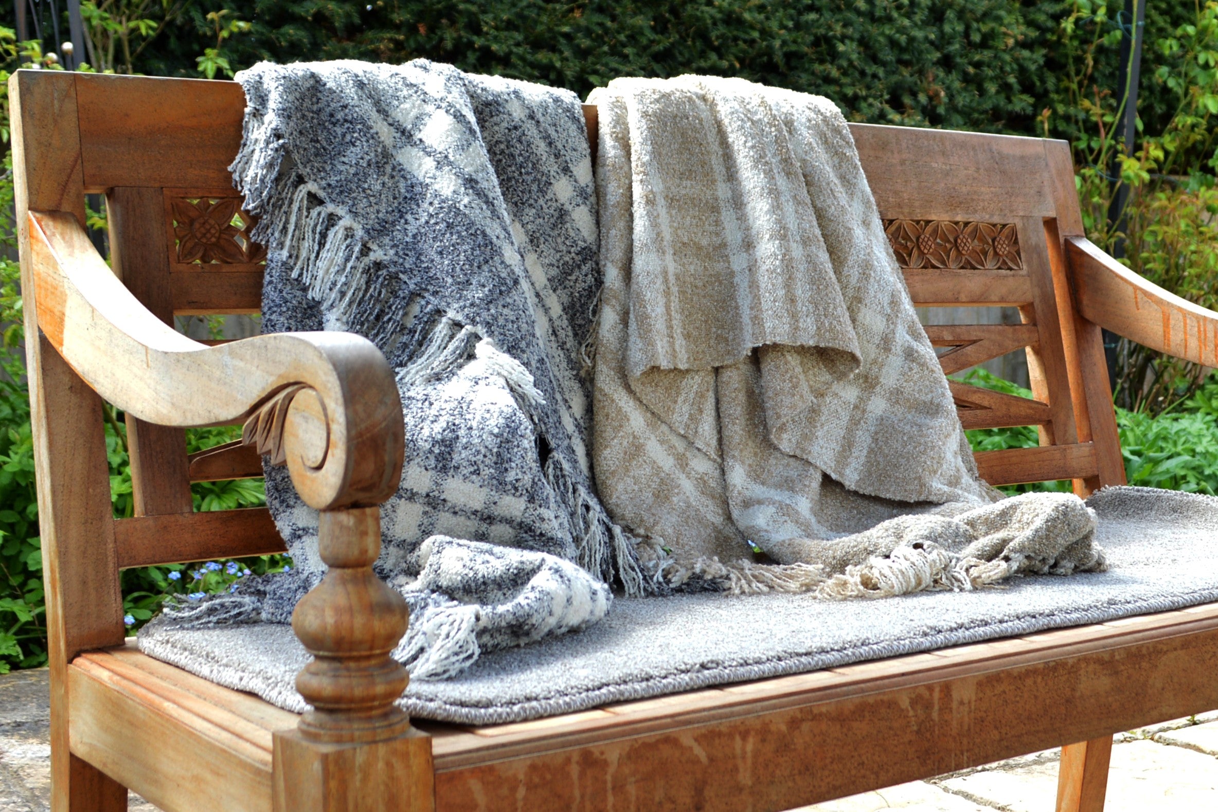 Two check throw blankets on a garden bench