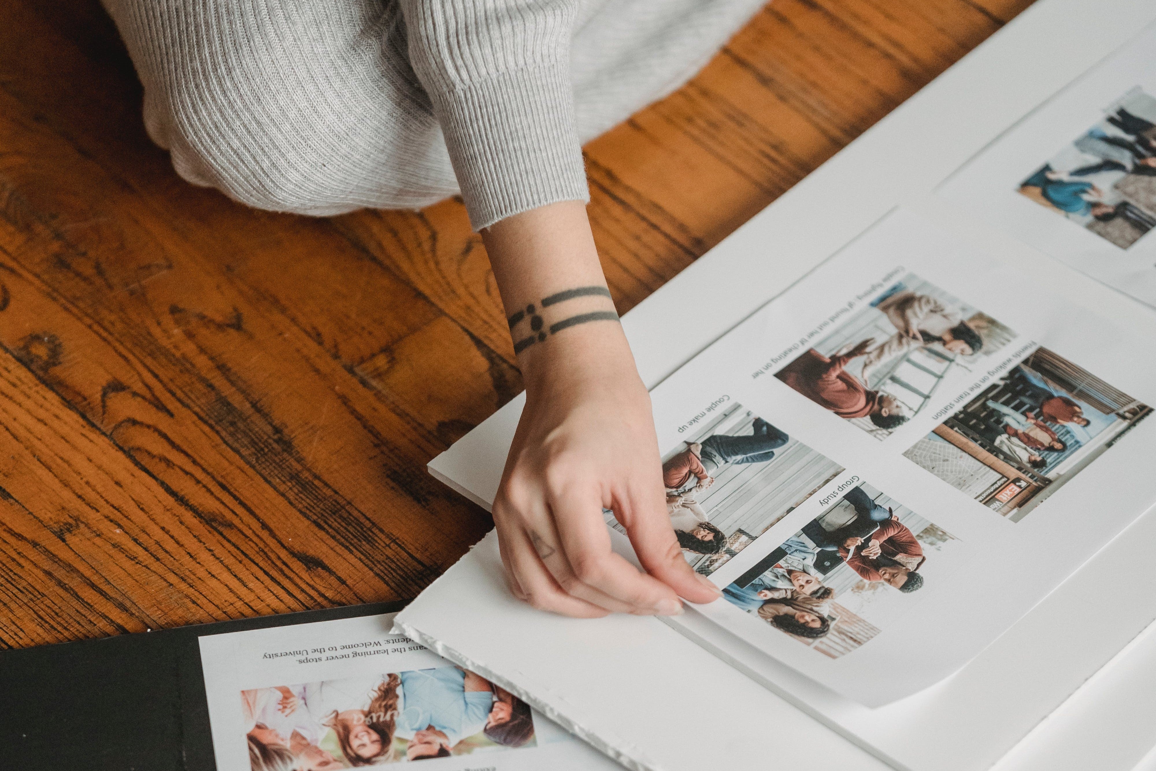 Crop unrecognizable woman forming photo album on floor