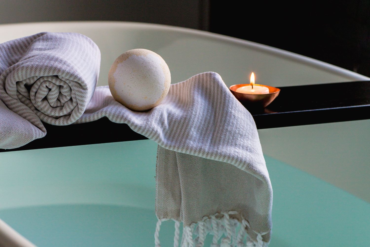 White Textile and Bath Bomb Beside Lit Candle