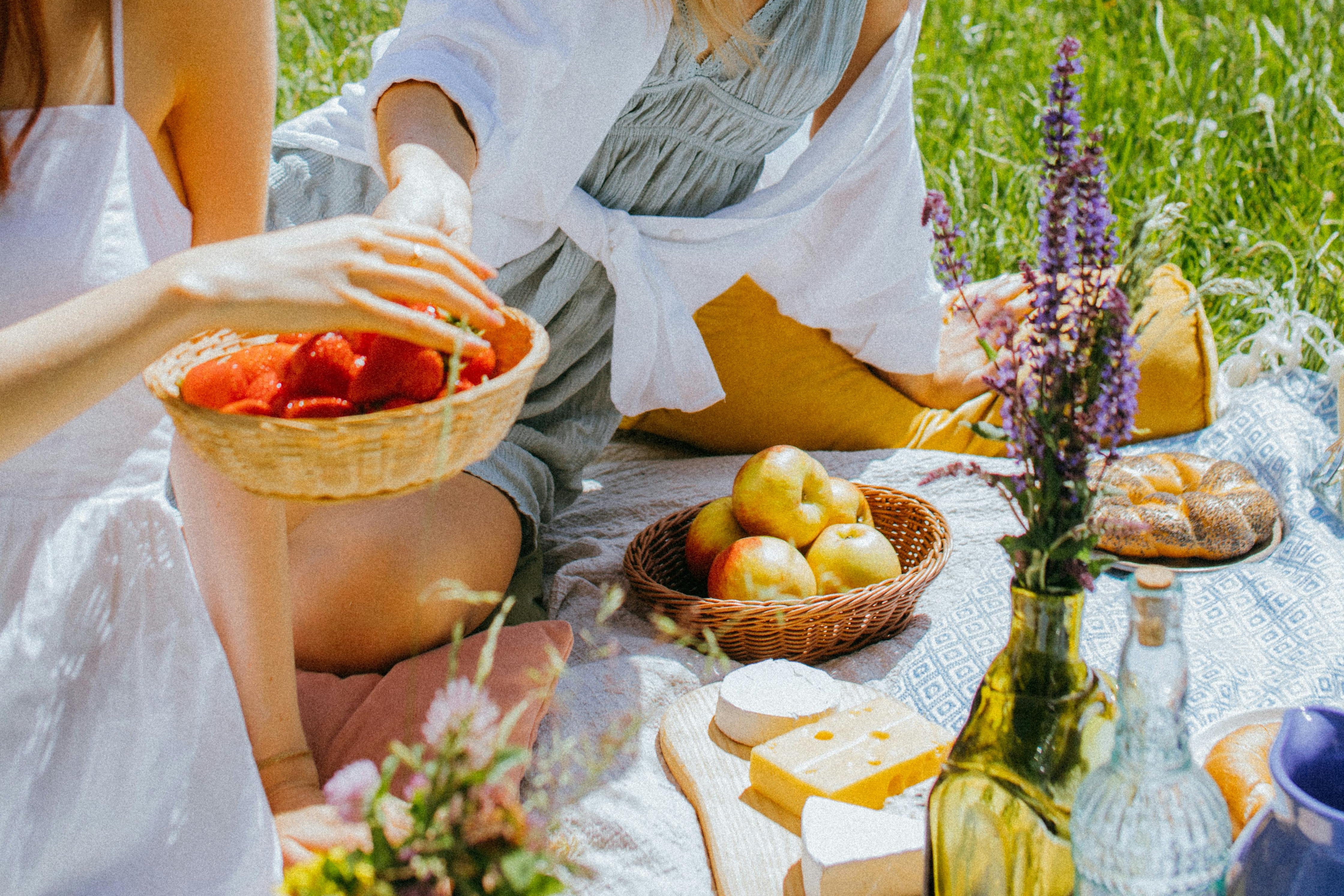 Women Sitting on a Picnic Blanket while Eating