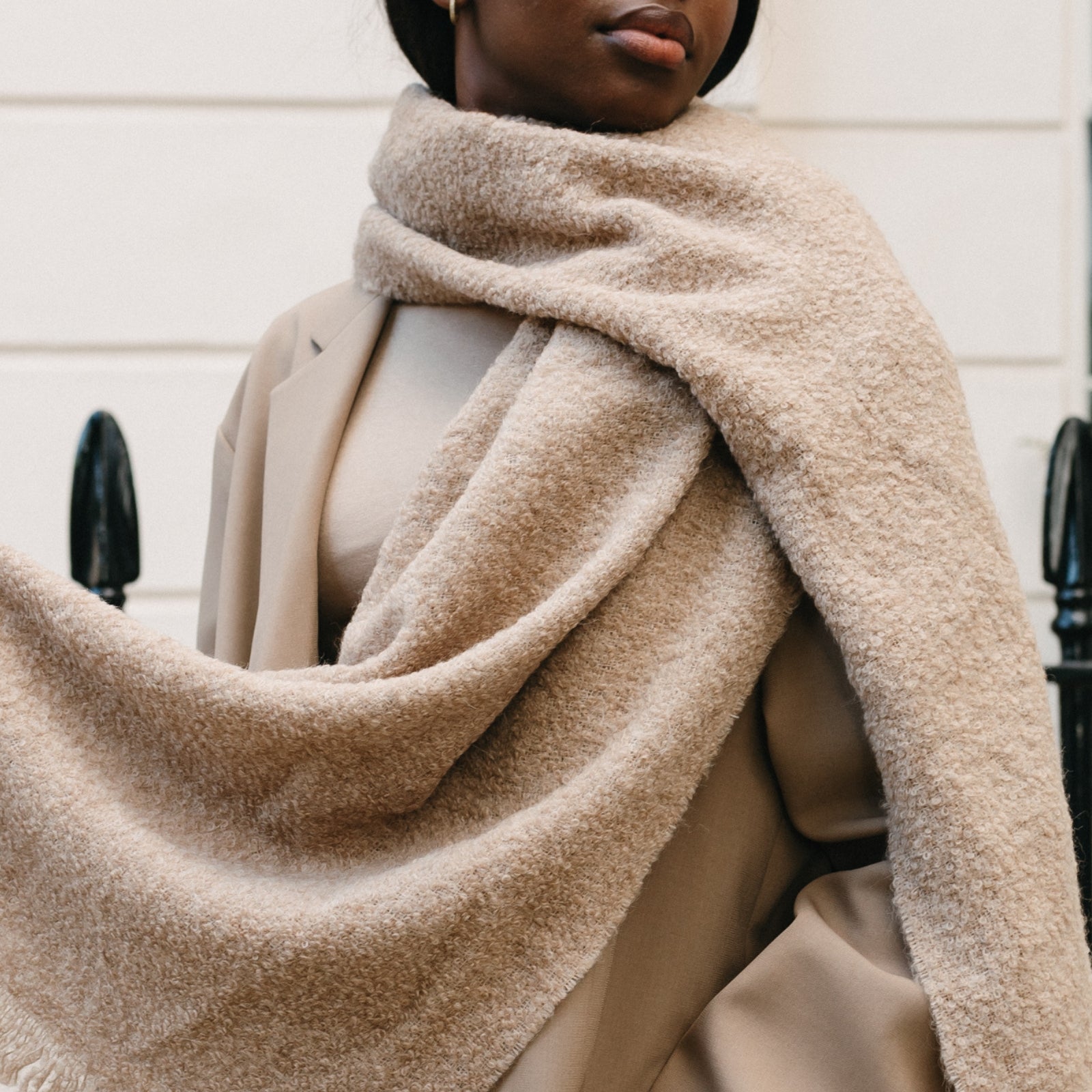 Model wearing camel coloured alpaca scarf