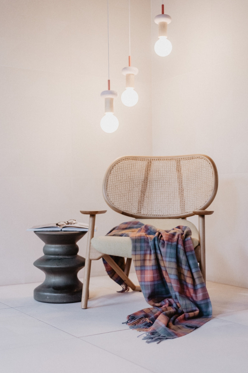 Modern wooden and cane armchair draped with tartan lambswool blanket