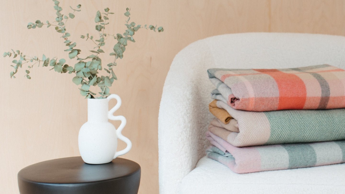 Stack of colourful recycled wool blankets on a fluffy tub chair