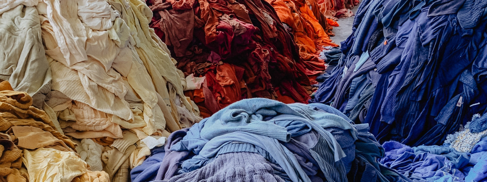 Piles of recycled dyed garments organised by colour