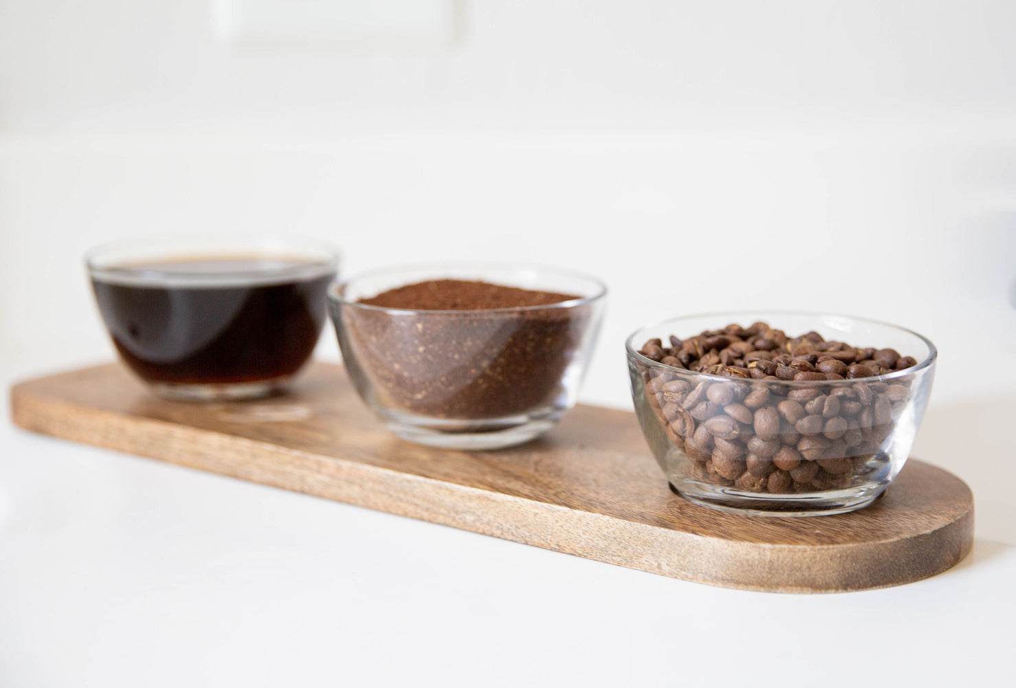 A display tray of coffee beans, grounds, and brewed coffee.