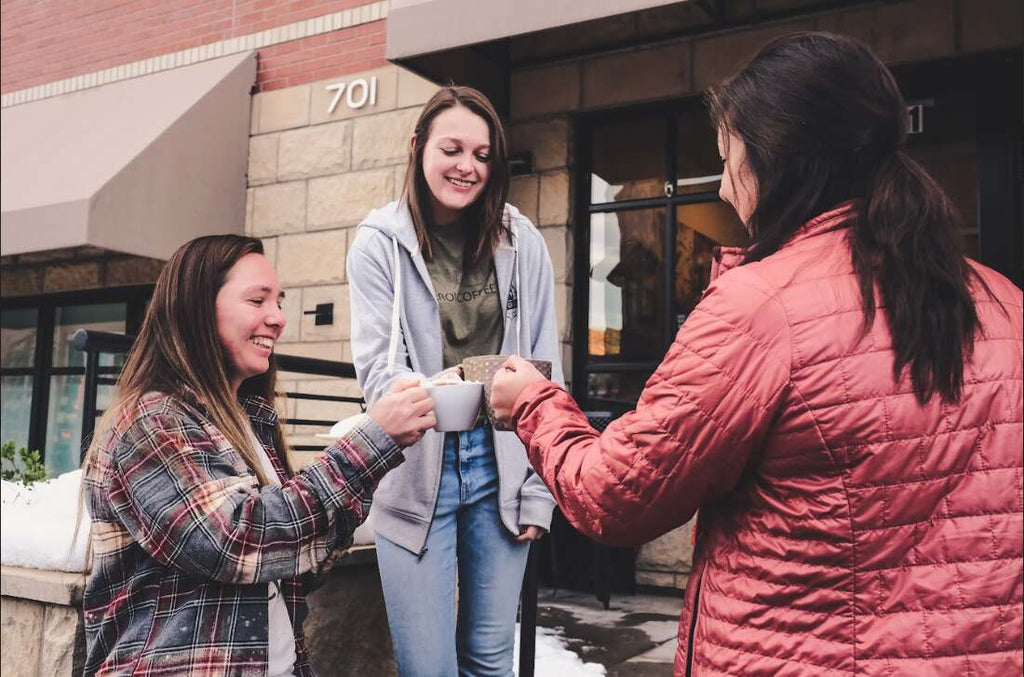 Girls clinking coffee mugs together