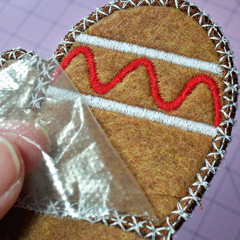 Picture of heat away film easily tearing away from edges on top of Christmas Cookies machine applique design.