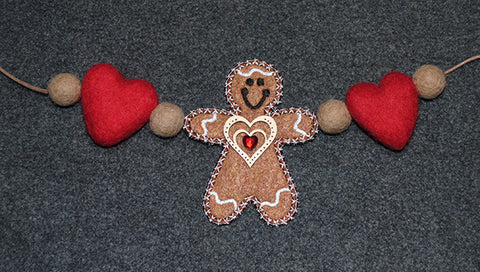 Picture of free-standing machine applique gingerbread man with latte felt balls and hearts attached to make garland.