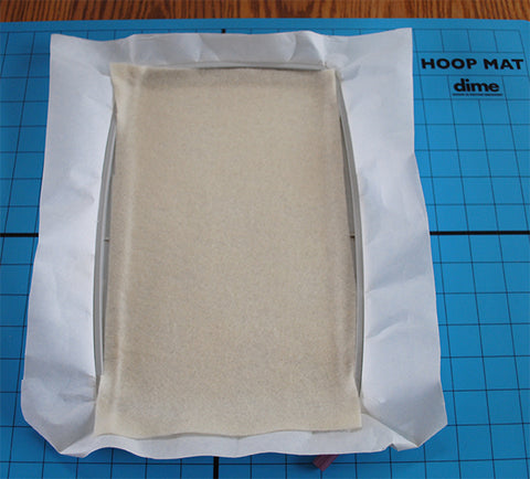 Picture of hooped fabric with stabilizer for machine embroidery.
