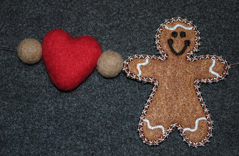 Picture of free-standing machine embroidered gingerbread man with latte felted heart and balls attached to arm.