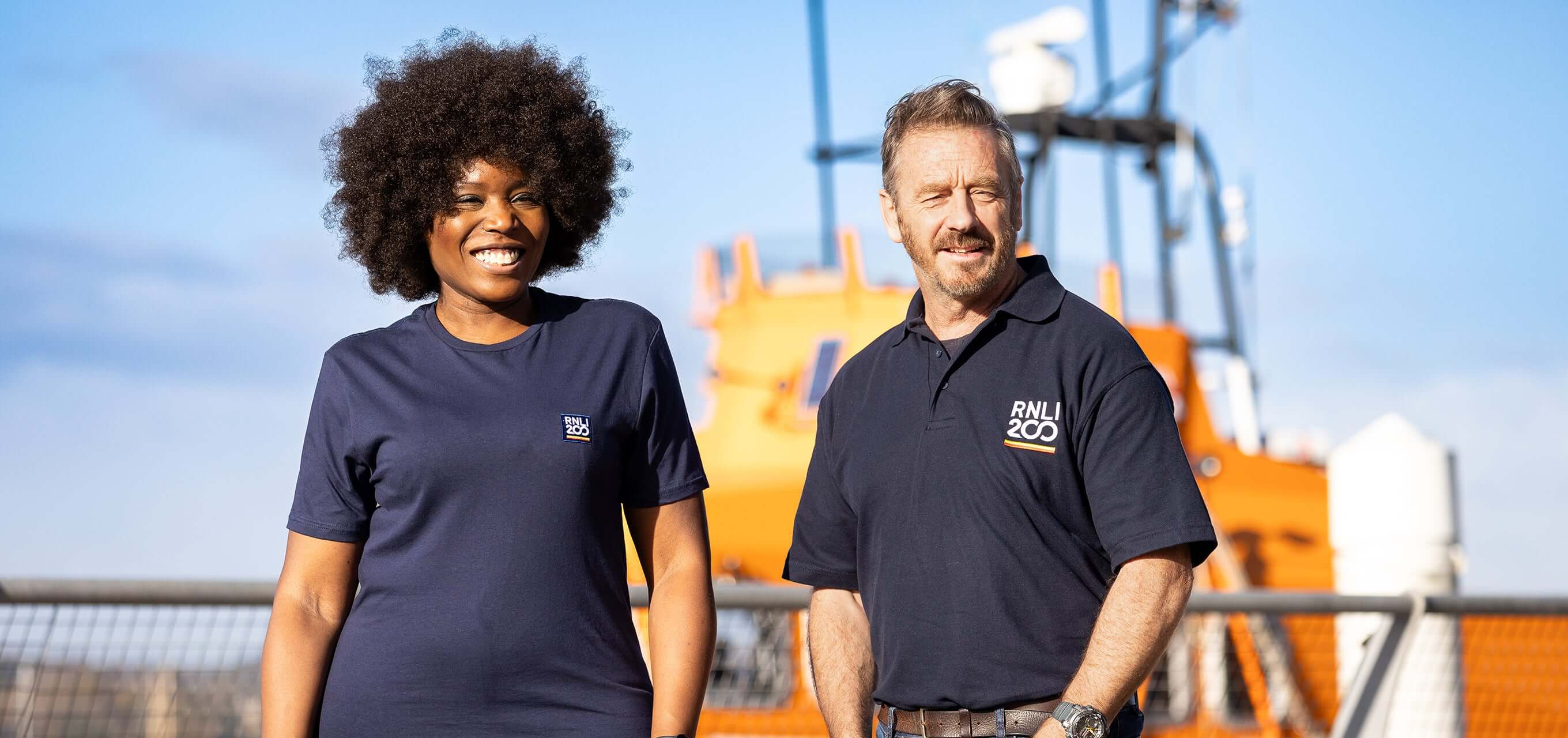 Two RNLI supporters standing in front of a lifeboat.