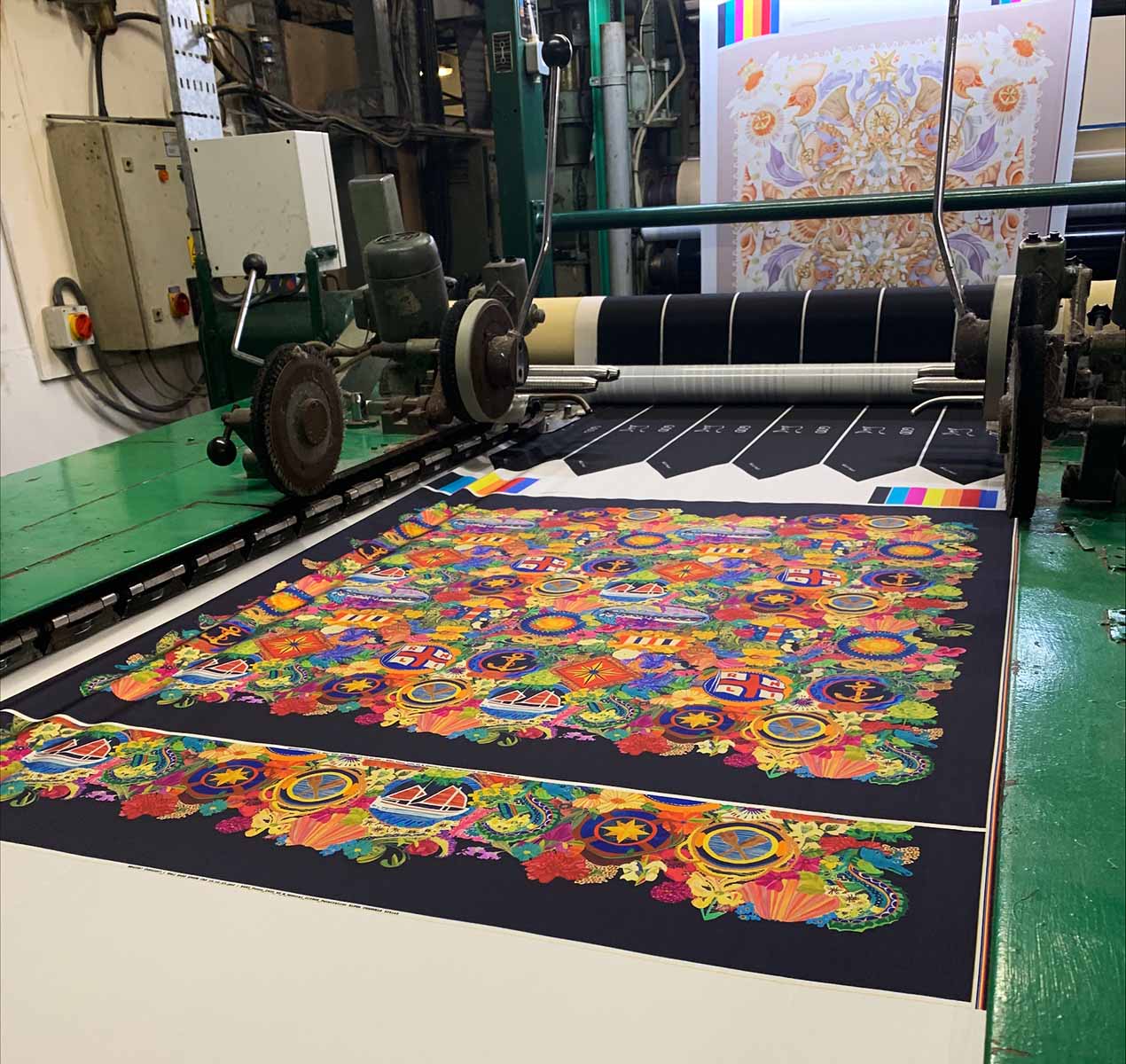 A colourful silk scarf is laid out on a machine in a workshop.