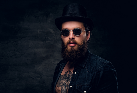 A man with a full beard wearing a hat and dark sunglasses