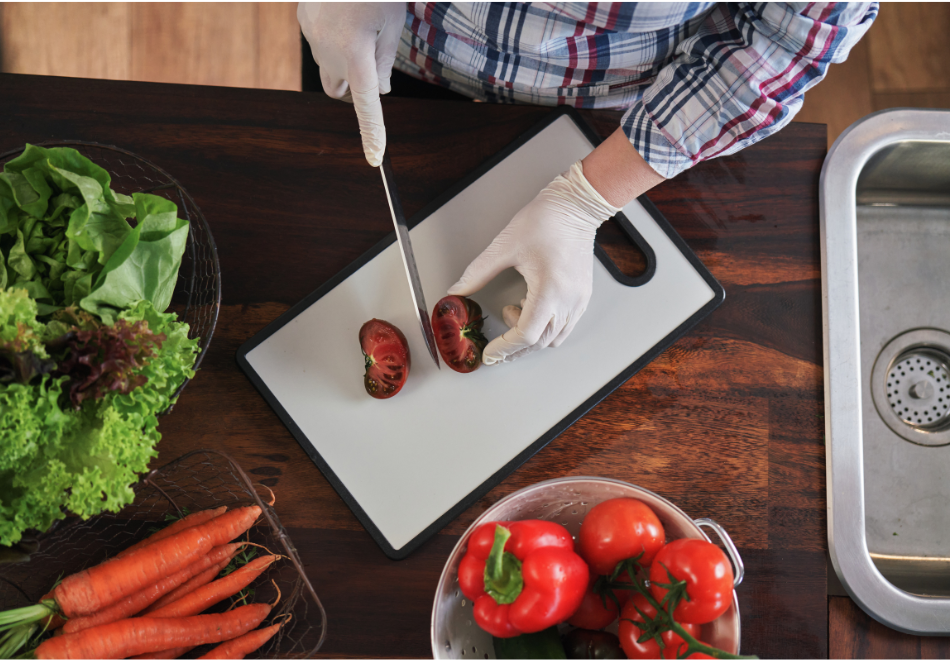 person wearing pvc vinyl gloves and cutting produce