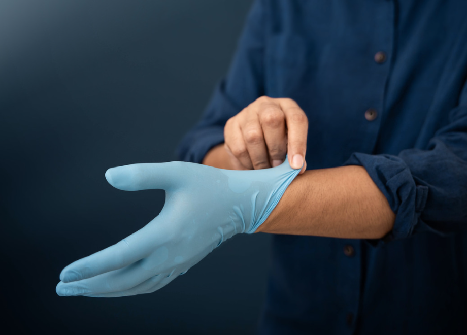 person pulling on a blue nitrile glove