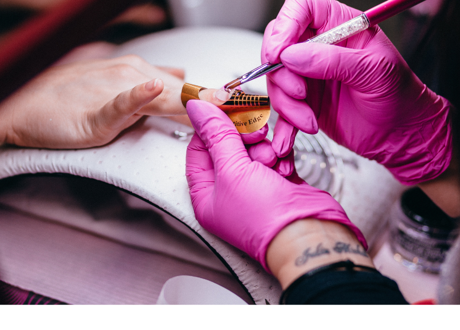 a person wearing pink gloves is giving another person a manicure