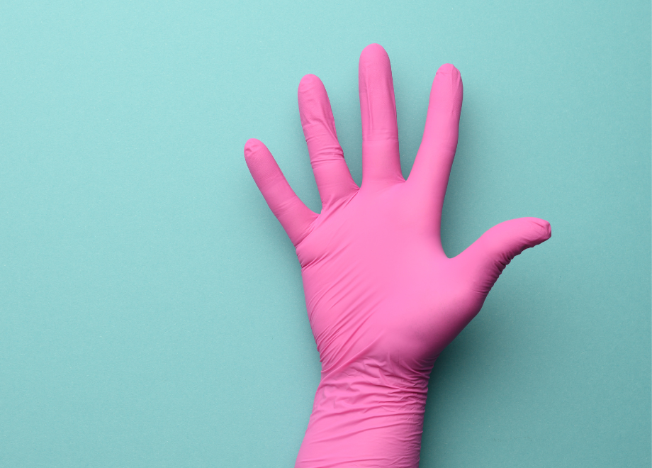 a hand wearing a disposable pink glove against a light greenish-blue background