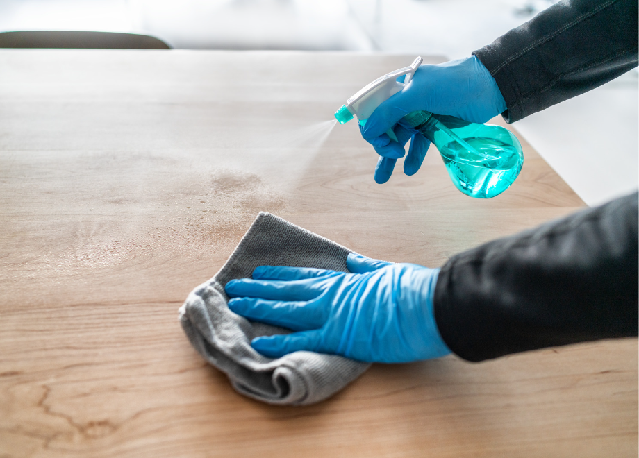 person wearing blue nitrile gloves and wiping a counter