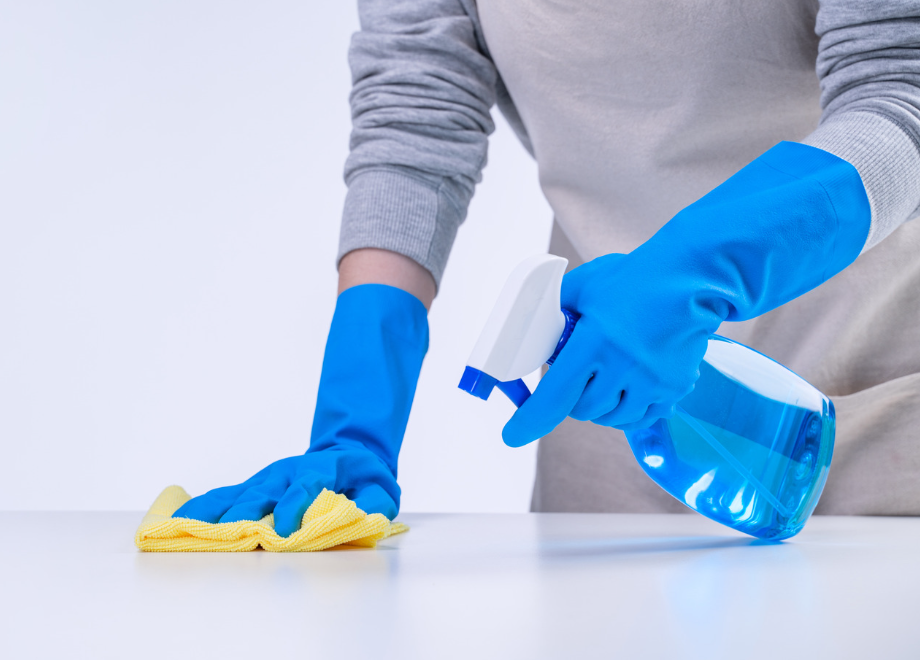 person wearing blue latex gloves and wiping counters