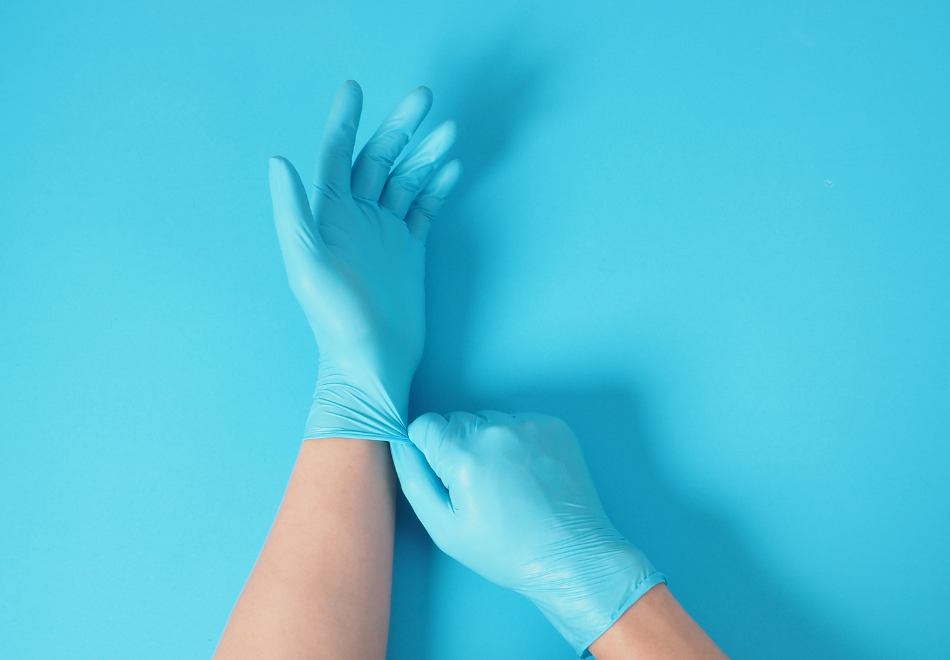 person pulling on blue nitrile gloves and checking their thickness