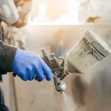 person wearing blue nitrile glove and spray painting