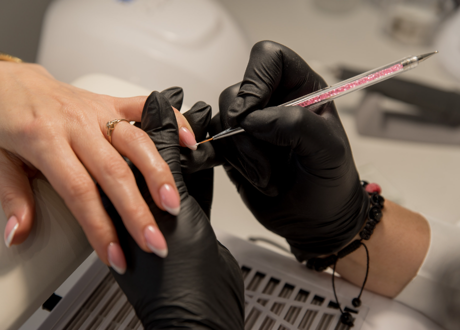 nail tech wearing black disposable gloves and giving a manicure