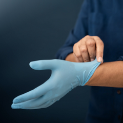 person pulling on a blue nitrile glove