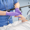 Nurse wearing purple grape grip nitrile gloves and caring for a patient
