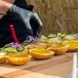 person wearing black nitrile gloves and prepping burgers