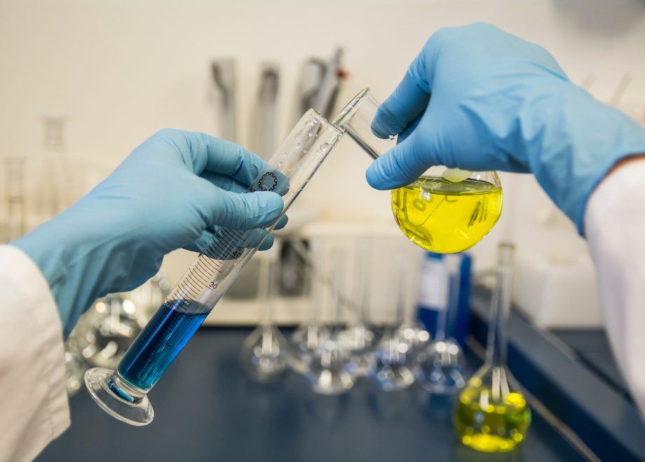 person wearing blue nitrile gloves and pouring chemicals