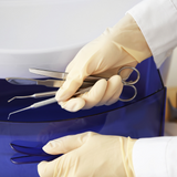 doctor wearing sterile gloves and setting out surgical instruments