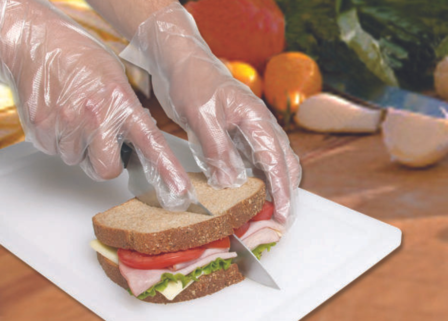 person wearing poly gloves and cutting a sandwich 