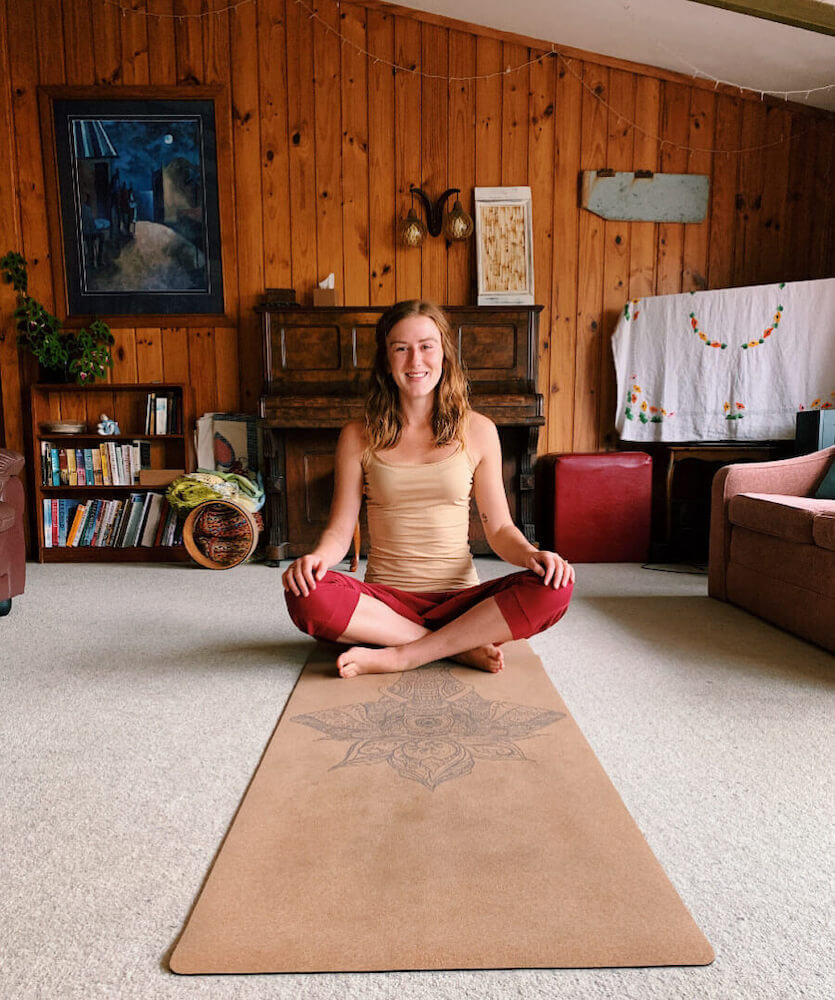 Ethically Kate sitting cross legged on a cork yoga mat