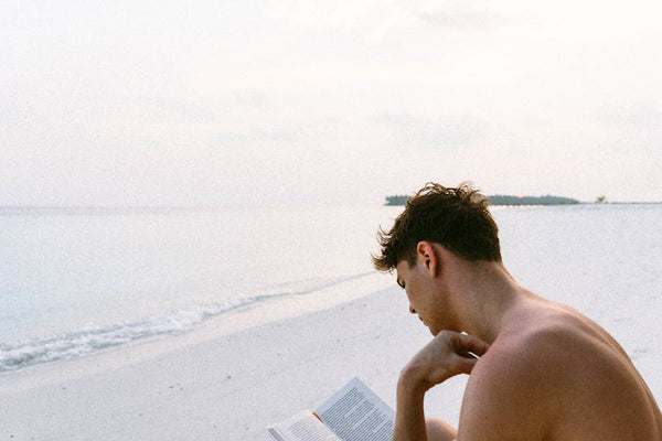 Man reading book by the beach