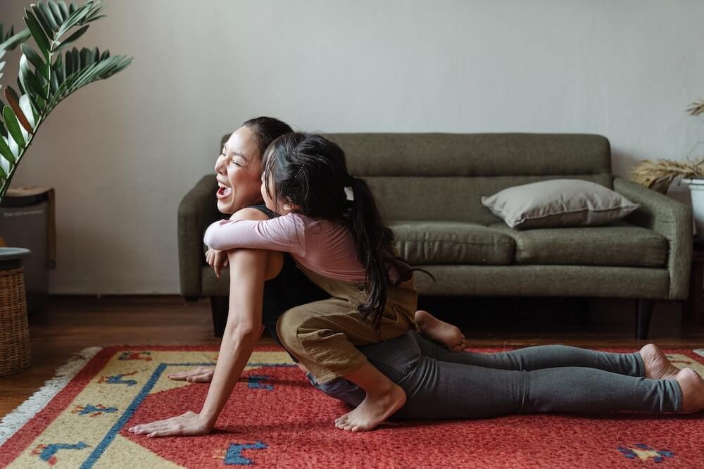 Mother and daughter playing while doing yoga