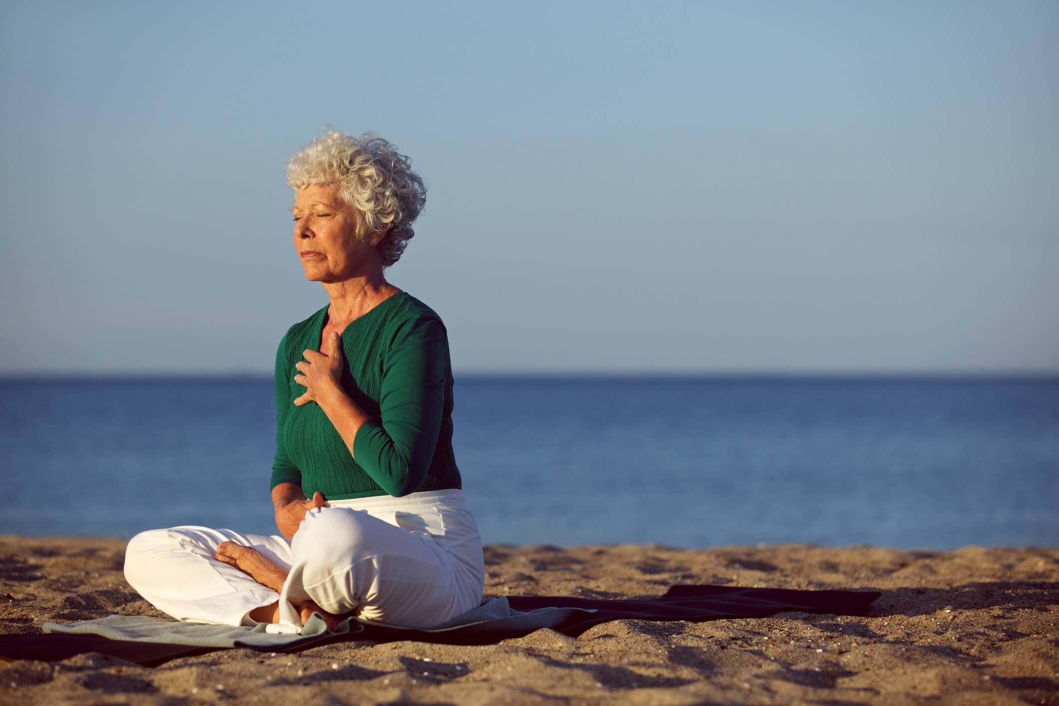 senior lady meditating on beach